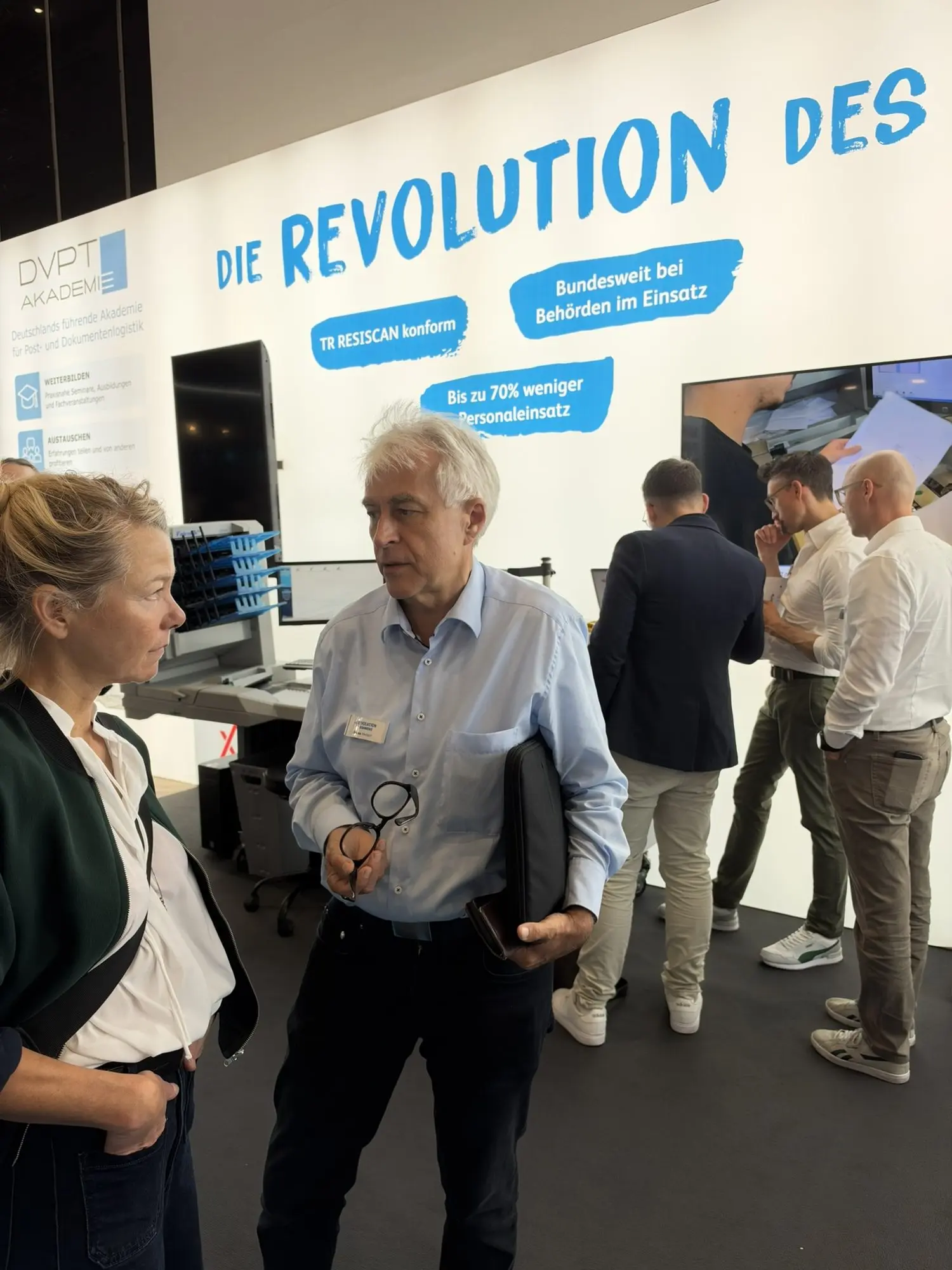 Eine Besucherin im Gespräch mit einem Mann mit Mappe am Stand