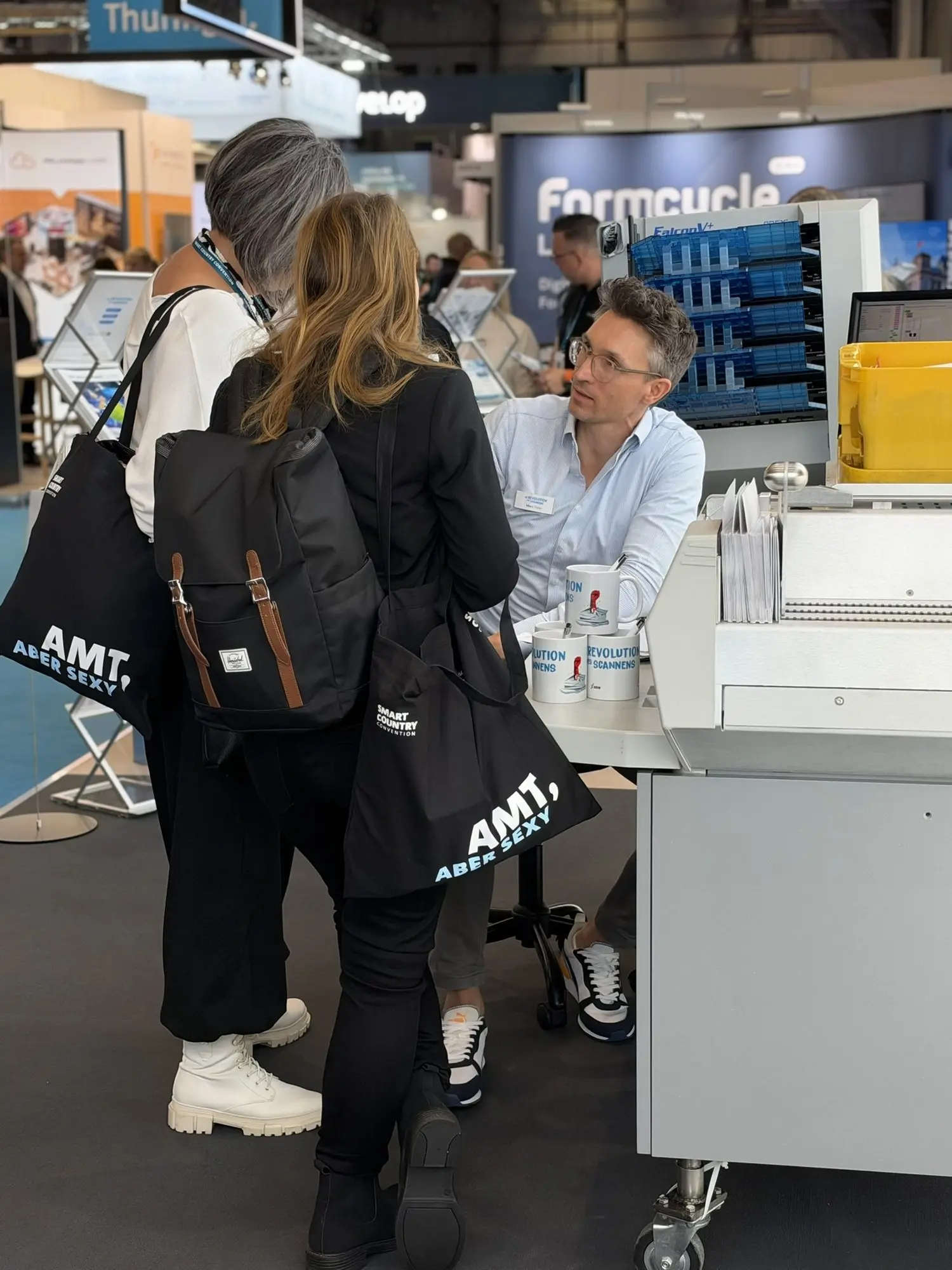 Besucherinnen am Scanarbeitsplatz, ein X-NRW-Mitarbeiter erklärt im Sitzen